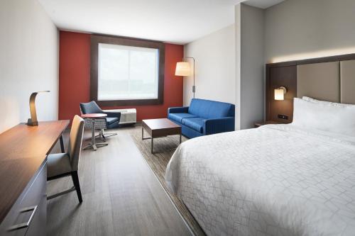 Holiday Inn Express & Suites Lubbock Central - Univ Area, an IHG Hotel في لوبوك: غرفه فندقيه بسرير ومكتب وكراسي
