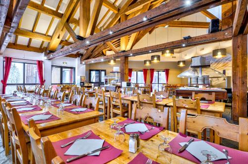 une grande salle à manger avec tables et chaises en bois dans l'établissement Village Club Les Tavaillons, aux Carroz d'Arâches