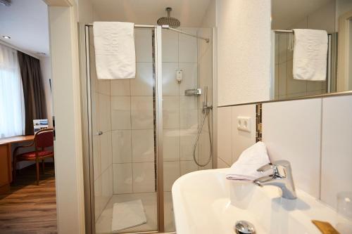 a bathroom with a glass shower and a sink at Flair Hotel Grüner Baum in Donaueschingen