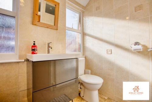 a bathroom with a toilet and a sink and a window at Bridgwater Bliss: 6-Bedroom Haven for Large Groups in Bridgwater
