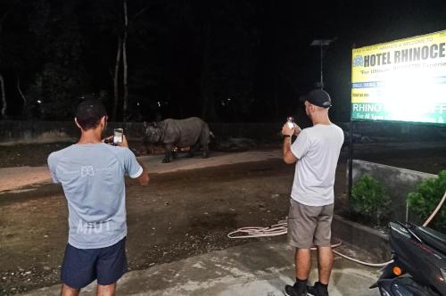 two men taking pictures of a rhino at night at Hotel Rhinoceros-Homestay in Sauraha