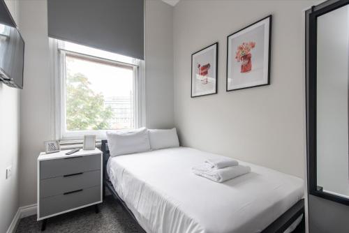 a white bedroom with a bed and a window at 6-Bedroom Apartments at the Heart of Nottingham in Nottingham
