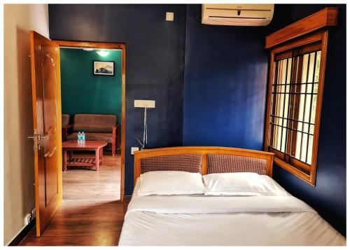 1 dormitorio con cama y pared azul en Ramana Towers en Tiruvannāmalai