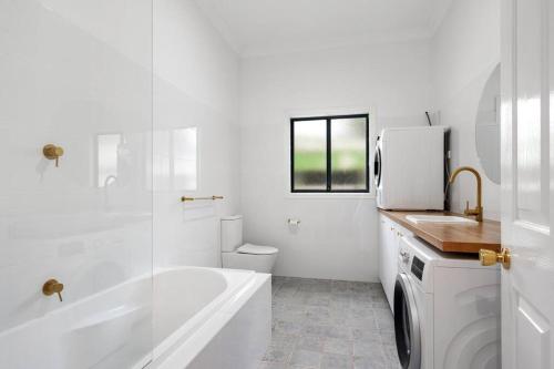 a white bathroom with a tub and a toilet and a sink at Super House, Super Host in Kalgoorlie