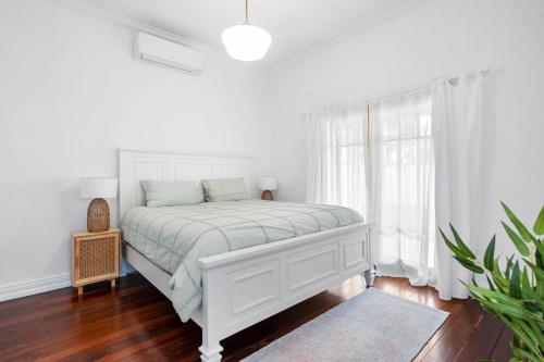a white bedroom with a white bed and a window at Super House, Super Host in Kalgoorlie