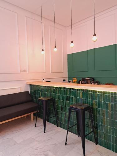 a kitchen with green and white cabinets and two stools at Riad Aïcha Kitchen in Marrakesh