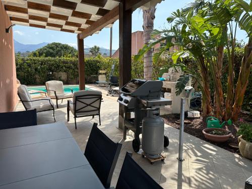 a barbecue grill on a patio with a pool at Villa con piscina riscaldata ad uso esclusivo, aperta tutto l'anno in Lascari