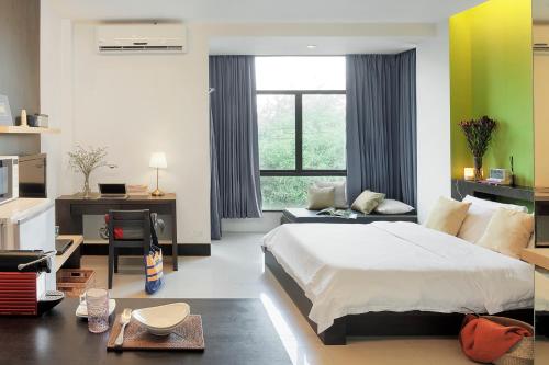 Schlafzimmer mit einem Bett, einem Schreibtisch und einem Fenster in der Unterkunft @Home Residence in Bangkok