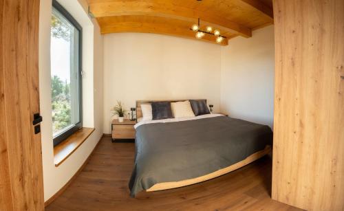a bedroom with a bed and a large window at Hortus Vita Wellness Apartments in Lipnice nad Sázavou