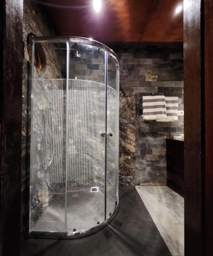 a glass shower in a room with a stone wall at Avalon Ubud Castle & SPA in Ubud