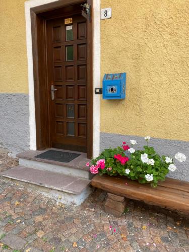a door with a bench with flowers in front of it at Casa Mia Fiemme in Carano