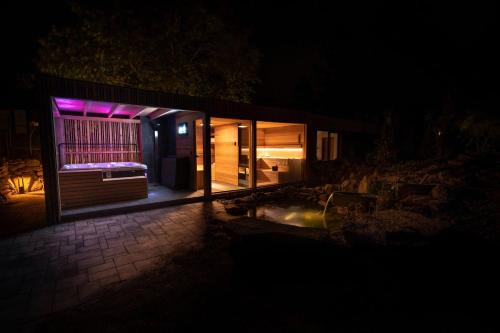 a house lit up at night with purple lights at Hortus Vita Wellness Apartments in Lipnice nad Sázavou