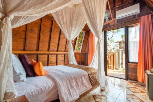 a bedroom with a bed with a canopy at Mai Mucuk Lumbung in Canggu