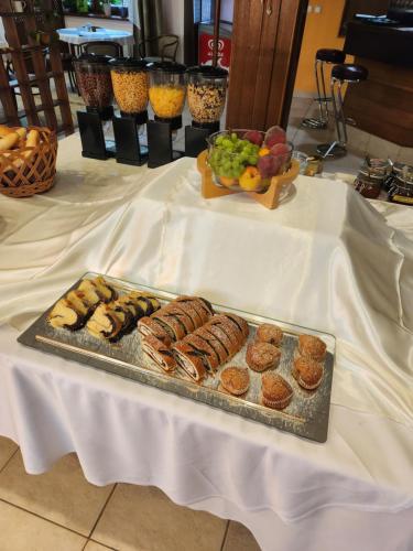 a table with a tray of pastries and a plate of fruit at Hotel Autis in Vysoké Tatry