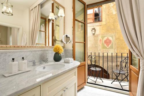 a bathroom with a sink and a mirror and a balcony at Luxury Apartments by Palazzo Portinari Salviati in Florence