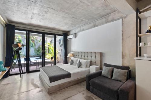 a bedroom with a bed and a chair at Balissimo Apartment by Hombali in Seminyak