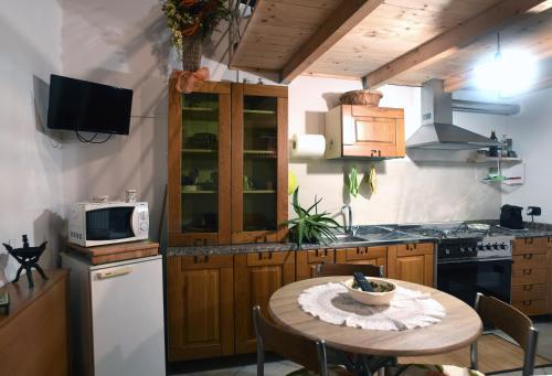 cocina con mesa, microondas y fogones en LA CASA SUL LARA, en Santo Stefano di Rogliano