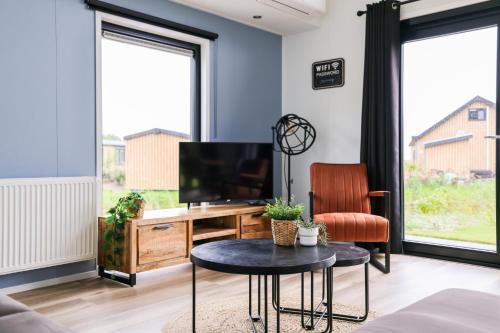 a living room with a tv and a table and a desk at Strandparc Nulde in Putten