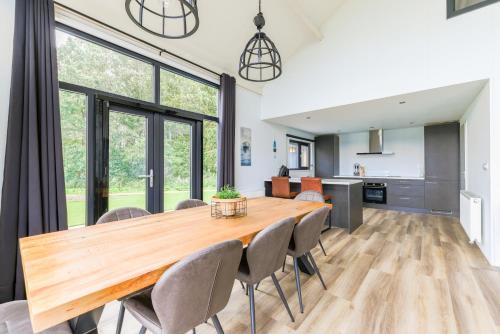 a dining room and kitchen with a wooden table and chairs at Strandparc Nulde in Putten