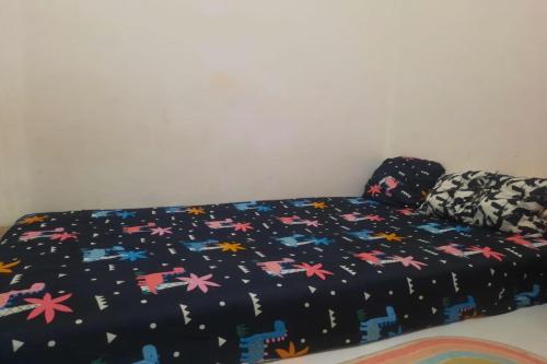 Una cama con un edredón negro con flores. en OYO Life 93160 Kost Jenny Karawang, en Karawang
