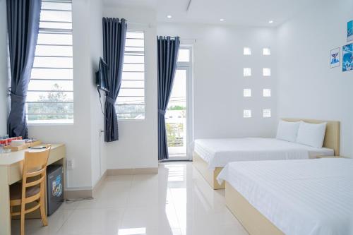 a bedroom with two beds and a desk and a table at An Gia Hotel Tây Ninh in Tây Ninh