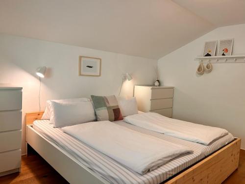 a bed with white sheets and pillows in a bedroom at Haus an der Drau nahe Velden / App. DRAU byTILLY in Velden am Wörthersee