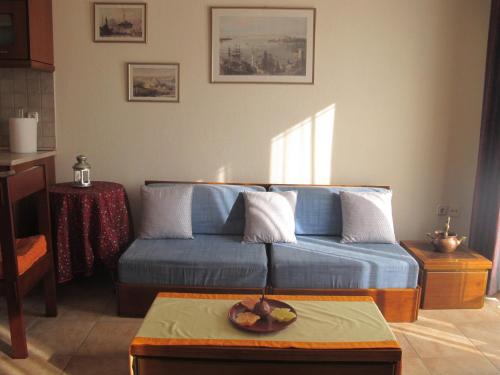 een woonkamer met een blauwe bank en een tafel bij One Home ~ Fits All in Mouzákion