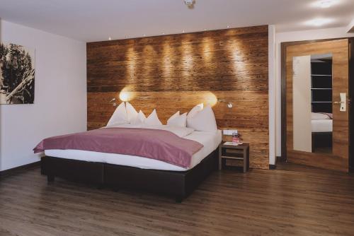 a bedroom with a bed with a wooden wall at Hotel DIE SONNE in Saalbach Hinterglemm