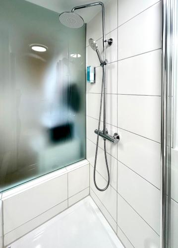 a shower with a glass door in a bathroom at The Manhattan A Boutique Hotel By American Ease in Gravenwerth