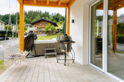 a patio with a hot tub and a grill on it at Bubbelen aan de piste in Kötschach