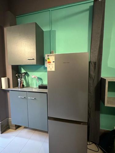 Il comprend une cuisine dotée d'un réfrigérateur et de murs verts. dans l'établissement Studio Détente Route du Maïdo, à Saint-Paul