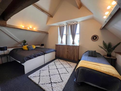 a attic bedroom with two beds and a window at Gites Le Bisson in Heussé