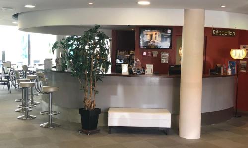 a bar in a restaurant with a bench and a table at Hôtel Le Palladior Voiron in Voiron