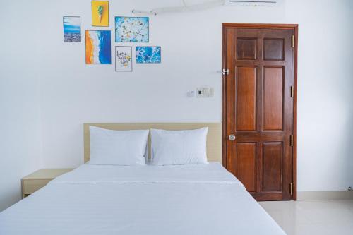 a bedroom with a white bed and a wooden door at An Gia Hotel Tây Ninh in Tây Ninh