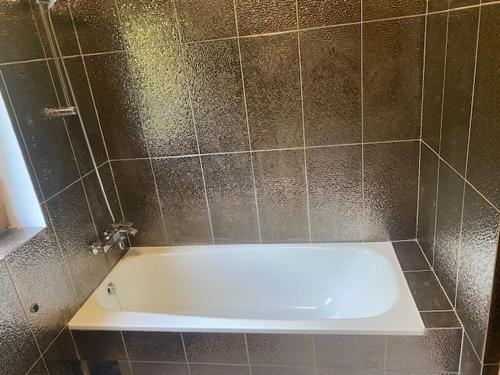 a bath tub in a bathroom with a tile wall at Ferienhaus Maximilian in Gamlitz