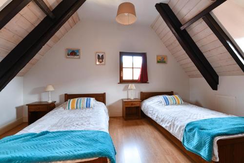 two beds in a room with white walls and wooden floors at Au Nid d'Hirondelles in Ribeauvillé