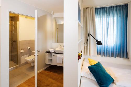 a bathroom with a bed and a sink and a toilet at SMARTments business Wien Heiligenstadt in Vienna