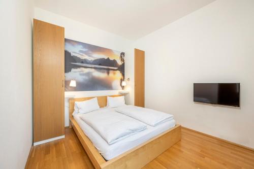 Schlafzimmer mit einem Bett und einem Flachbild-TV in der Unterkunft Apartment Gitti Obermoser in Radstadt