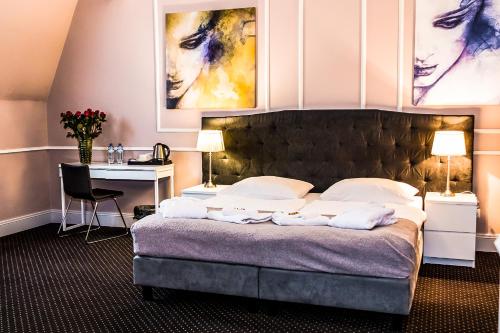 a bedroom with a large bed with a desk and a table at Aparthotel Platinum Apartamenty in Inowrocław