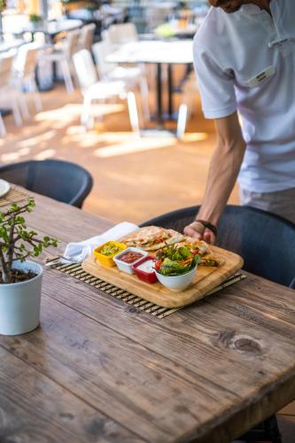 a person standing at a table with a tray of food at Kuum Hotel & Spa in Golturkbuku