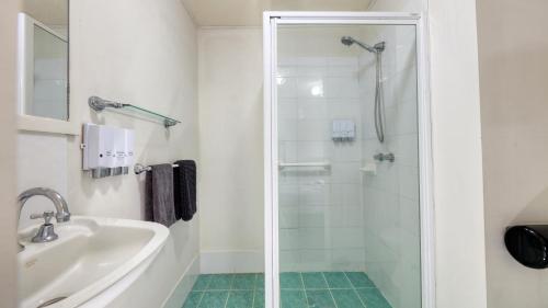 a bathroom with a shower and a sink at Oasis Motel in Peak Hill