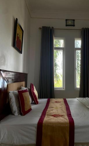 a bedroom with a large bed and two windows at Khách sạn Phương Đông in Hải Dương