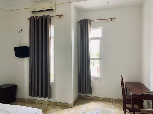 1 dormitorio con cortinas, escritorio y ventana en Khách sạn Phương Đông, en Hải Dương