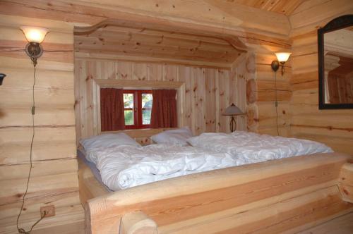 a large bed in a log cabin bedroom at Skibyen Jons Hytte in Skoro