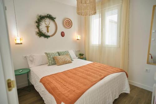 a bedroom with a bed with an orange blanket and a window at Vivienda Oasis Feria in Albacete