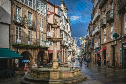 a street with a fountain in the middle of a city at Morar Ourense in Ourense
