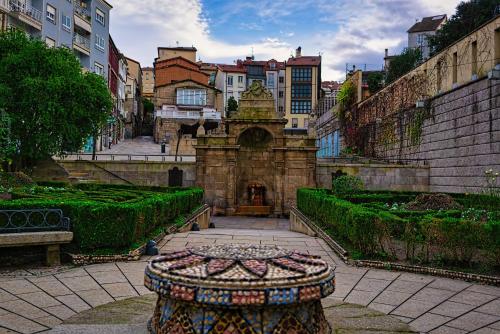 Morar Ourense في أورينس: نافورة في وسط مدينة بها مباني