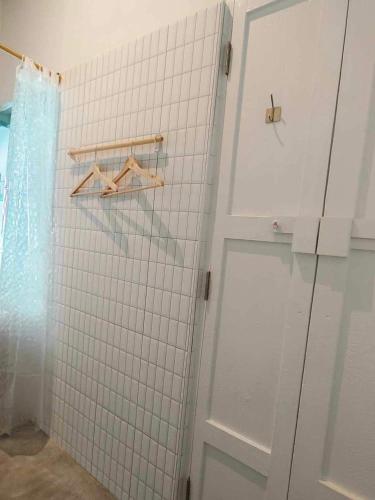a bathroom with a white tiled wall and a door at Mr Black & Ms White -Self Check in accommodation in Pom Prap