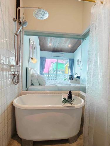 a bathroom with a tub with a bed in the background at Mr Black & Ms White -Self Check in accommodation in Pom Prap
