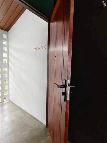 a wooden door in a room with a white wall at Mr Black & Ms White -Self Check in accommodation in Pom Prap